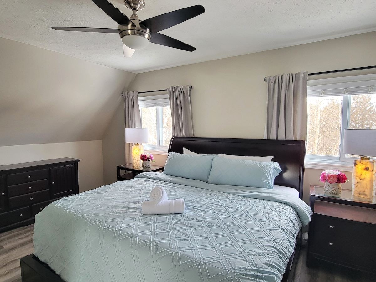 Loft bedroom with a king bed in pale blue linens under a sloped ceiling