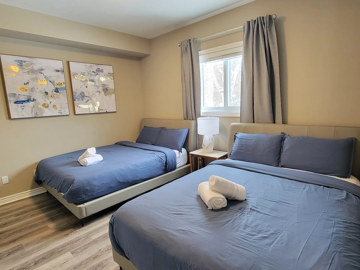 Main-floor bedroom with two queen beds in navy linens