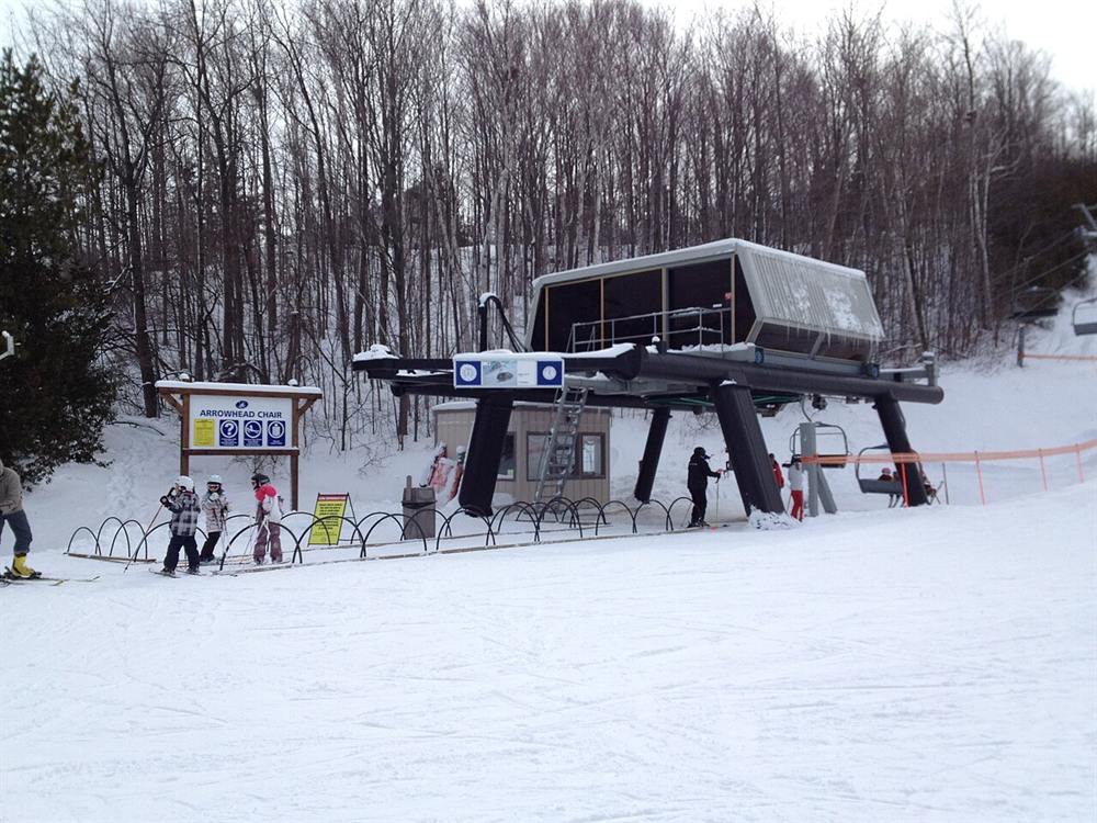 Skiers lining up at a chairlift on a snowy hill