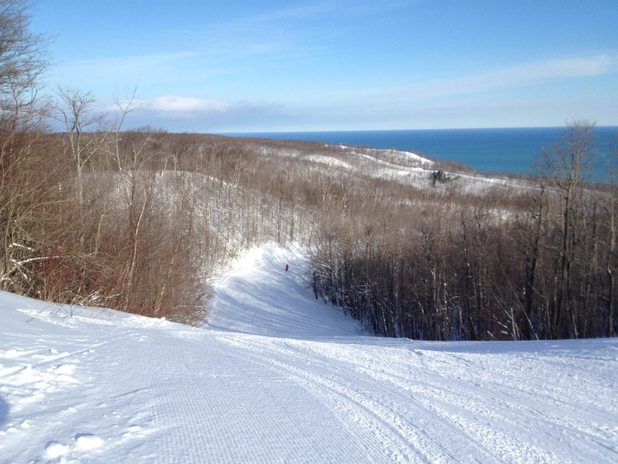 A freshly groomed ski run curving down toward the deep blue of Georgian Bay